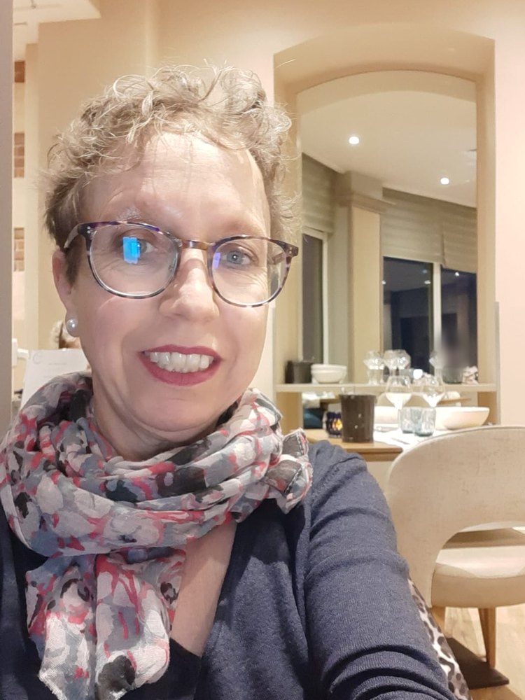 Emmanuelle Girard Mukuna, souriante, avec ses lunettes et un foulard.